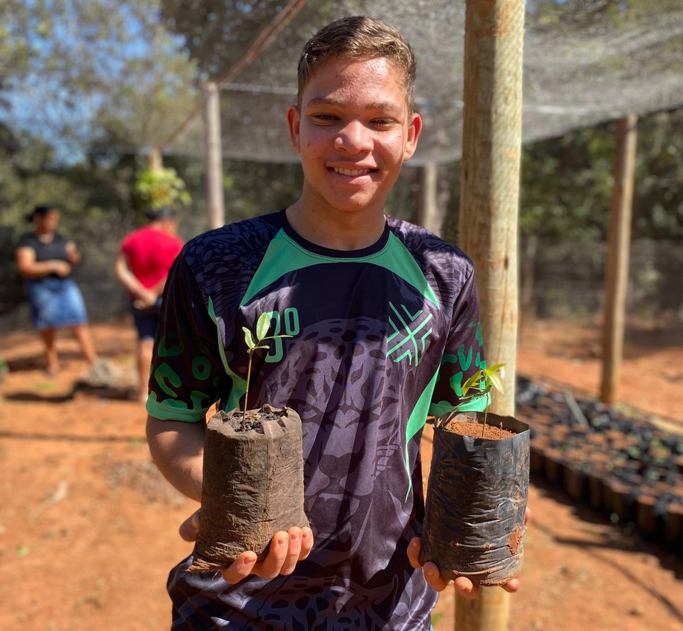 Jovem segurando mudas em atividade de campo